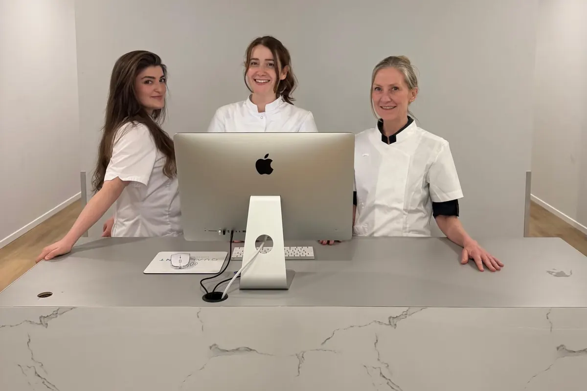 Drie medewerkers van Qualident achter de balie van de kliniek